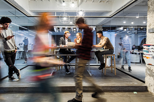 Young creative people working in the office among people in blurred motion.